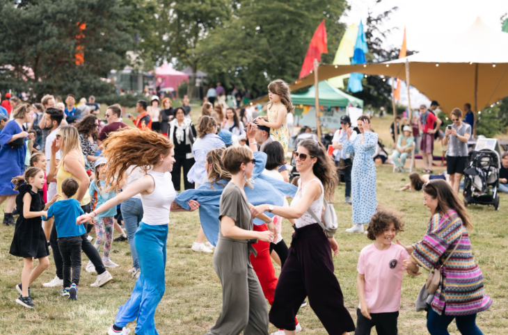 Families dancing together on grass at an open-air festival