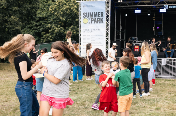 Children dancing in front of a stage in a park