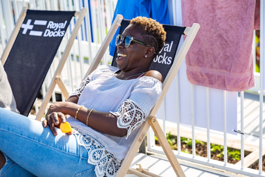 Beaches in London summer 2025: a woman relaxing in a Royal Docks branded deckchair