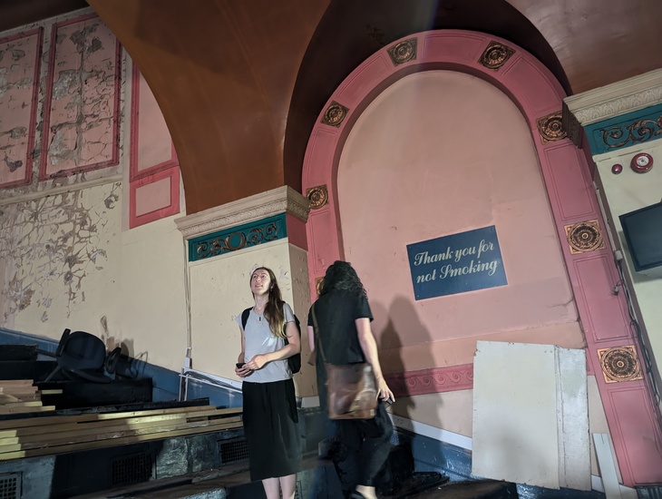 People exploring the cinema, and an old 'thank you for not smoking' sign
