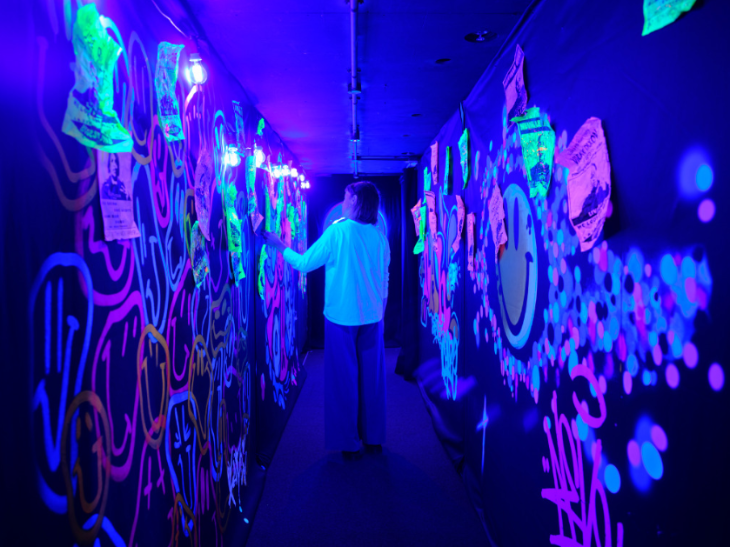 Things to do in London August 2025: someone walking down a dark corridor with neon paint on the walls