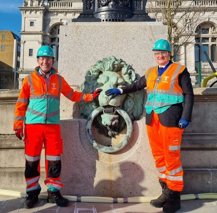 A lion mooring ring with two men in orange