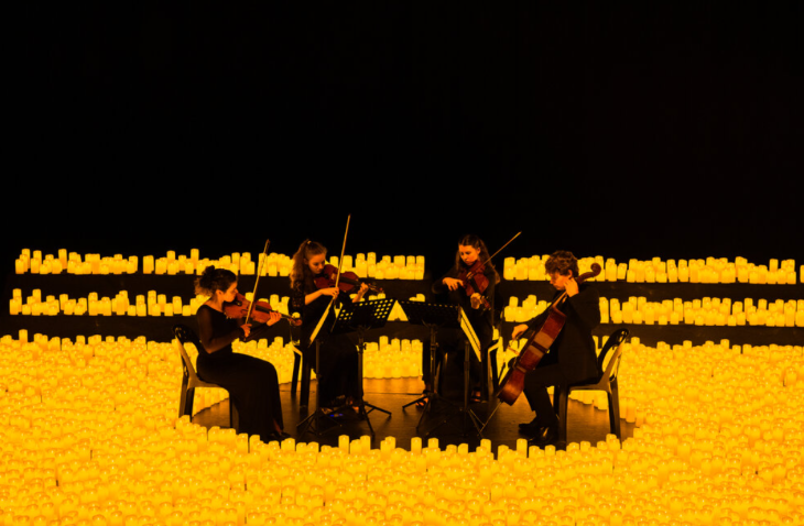 Things to do today in London: a string quartet on stage, surrounded by LED candles