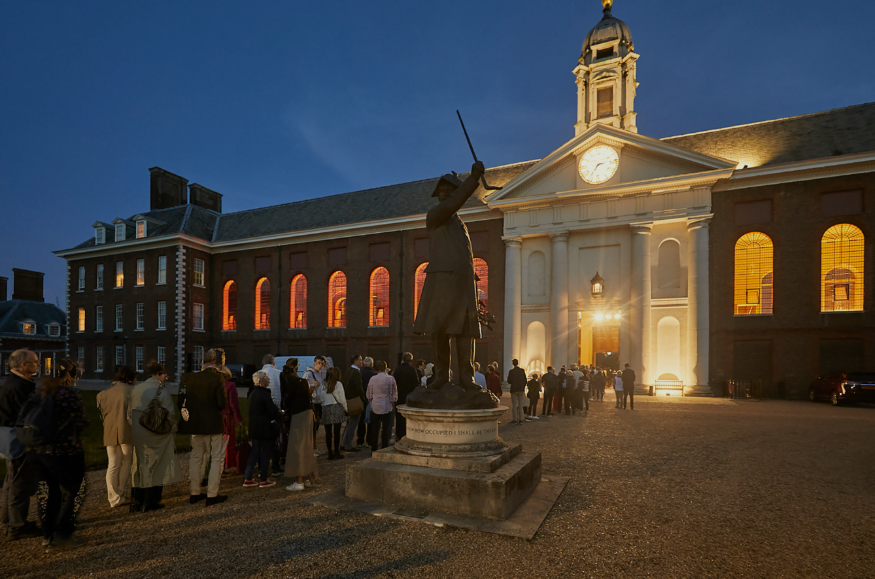 Chelsea History Festival 2025: people queuing to get into the Royal Hospital Chelsea at dusk