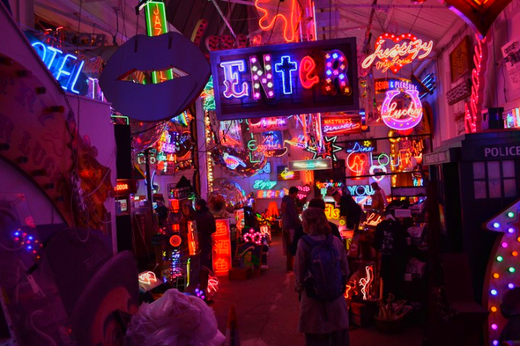 Interior of a dark warehouse with neon signs hanging all over the walls and from the ceiling