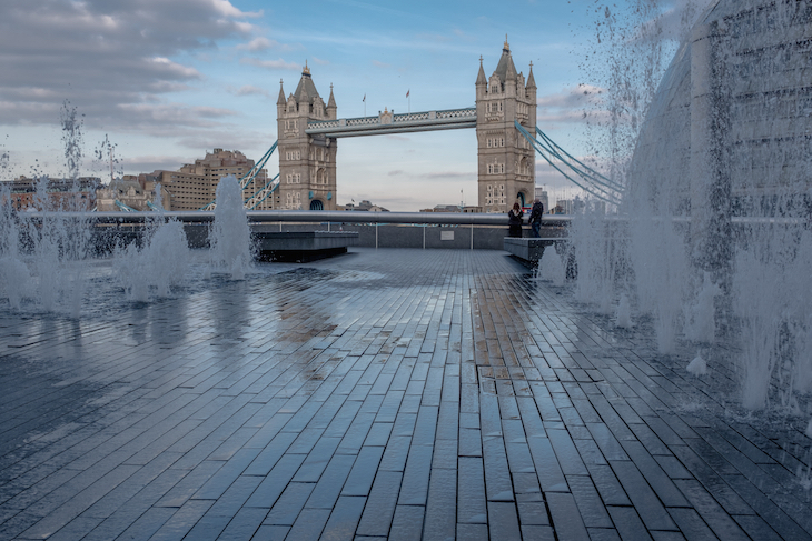 Fountains erupting from the pavement, with Tower Bridge in the background