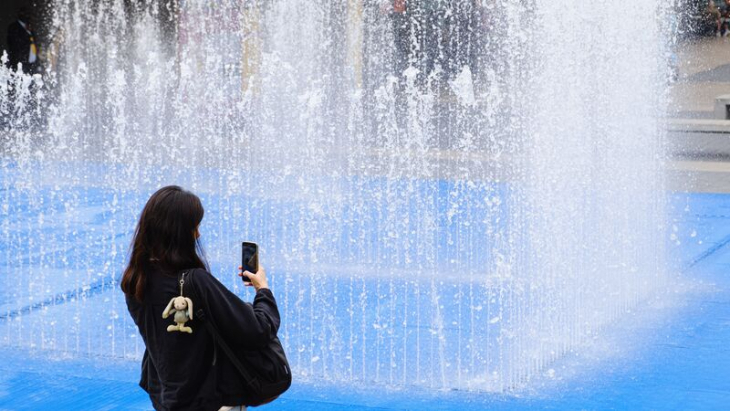 Play fountains in London: a woman taking a photo of a maze made from water fountains