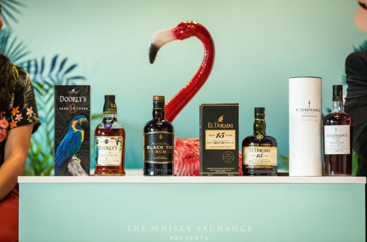A row of rum brands on a bar, with a flamingo model behind the bar