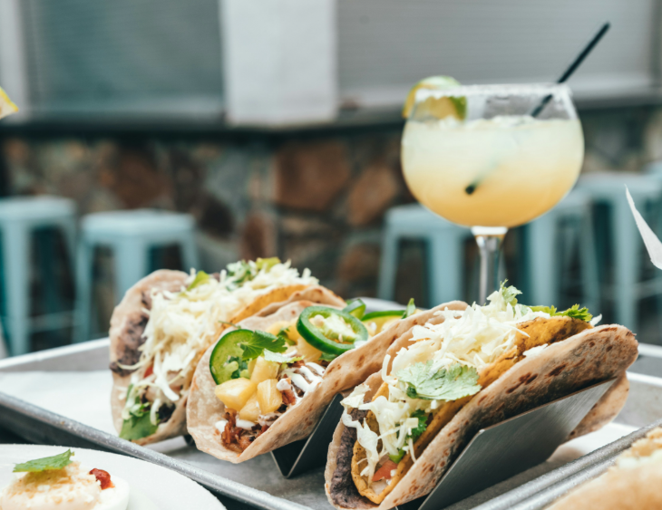 Things to do today in London:  three tacos on a plate with a cocktail in the background