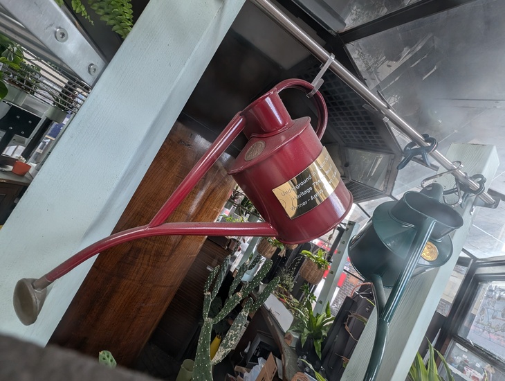 A watering can with a plaque on it, hanging up