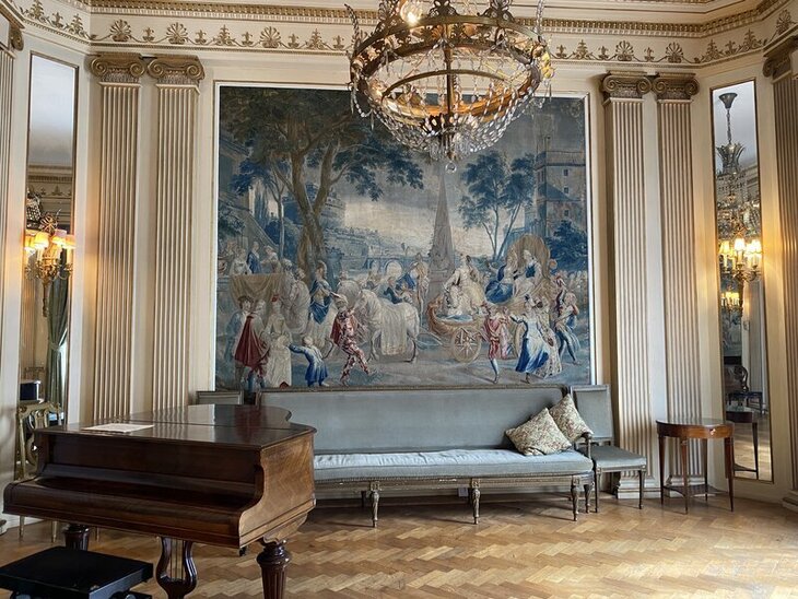 A room with a tapestry and grand piano