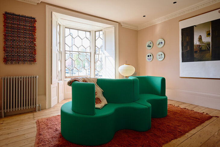 A curvy green sofa in a beautiful room