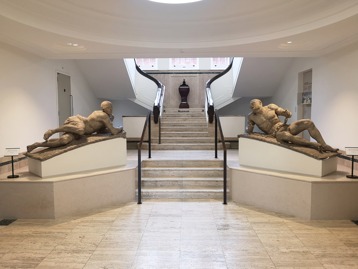 Two statues of 'mad' men flanking a staircase