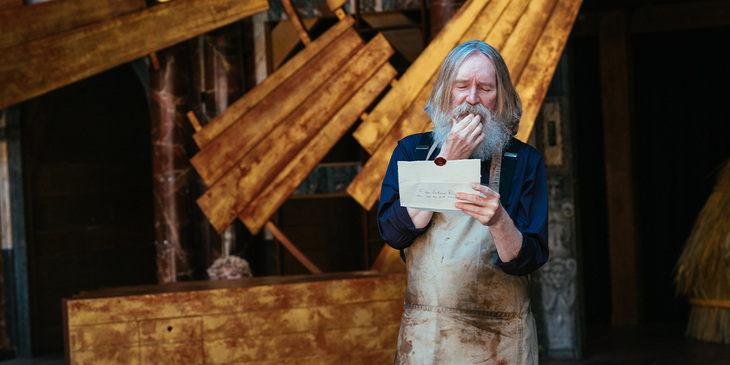 A bearded man reading a note