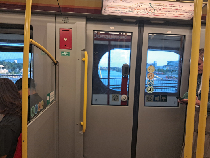 View from inside a carriage looking out at an oval shaped cutout in a concrete wall over the Danube