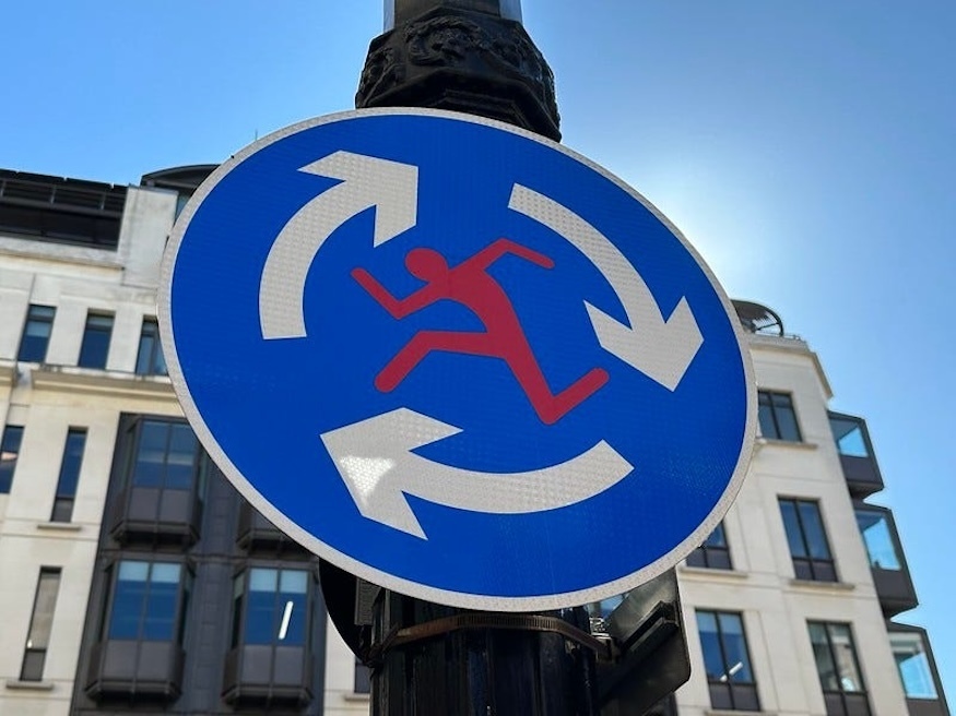 A roundabout sign with a running man in the middle, by Clet Abraham