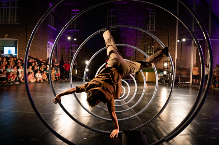 Free things to do in London this week: a performer doing a handstand inside a large metal spring, watched by an audience