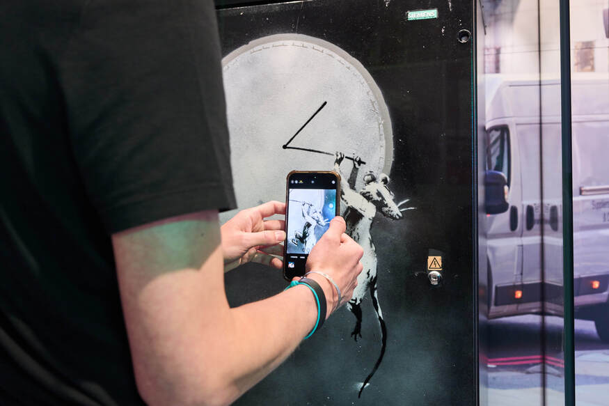Someone snapping a photo of the Banksy