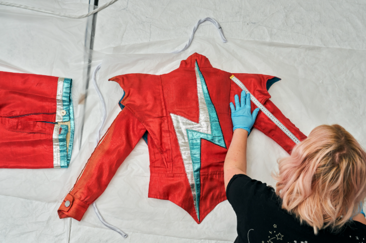 September 2025 events in London: a curator measuring a red jacket with a silver and blue lightning bolt on the back