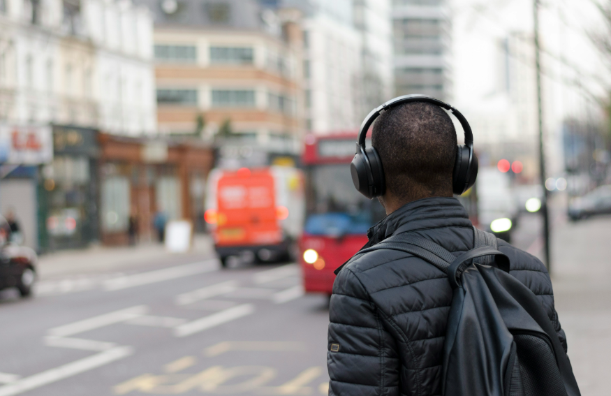 A man wearing headphones as a bus approaches