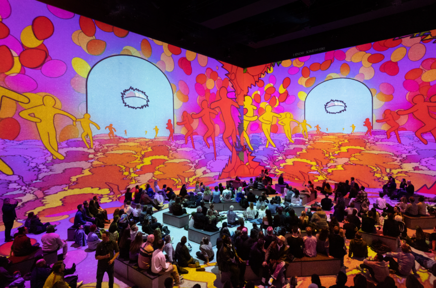 Things to do in London August bank holiday weekend: people sitting in a large room watching colourful video projections on the walls, floor and ceiling