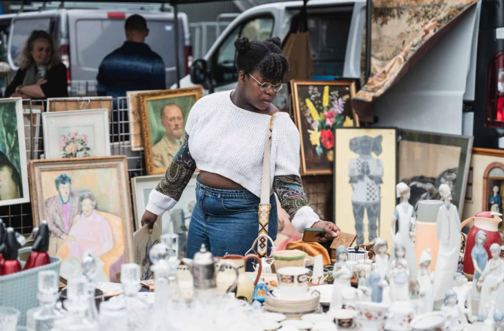 Things to do in London today: a woman browsing a stall at a flea market