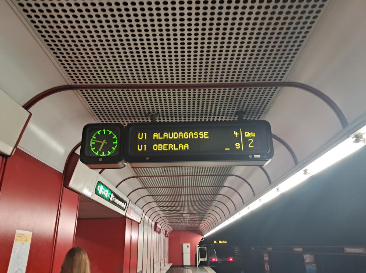 A light-up train indicator board on a platform indicating the times and destinations of the next trains