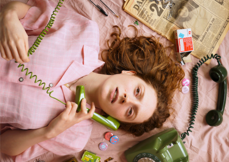 Things to do in London today:  a woman lying on a bed talking on a corded phone