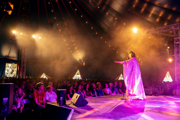 September 2025 events in London: a crowd sitting inside a big top tent, watching an act on stage