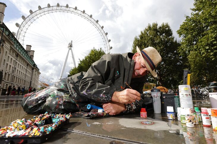 An artist painting on the floor in front of the London Eye