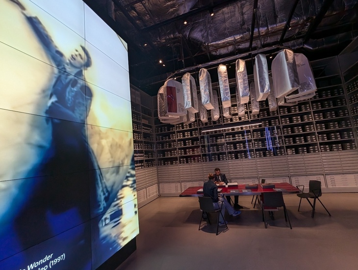 People studying next to a huge video screen with Bowie on it