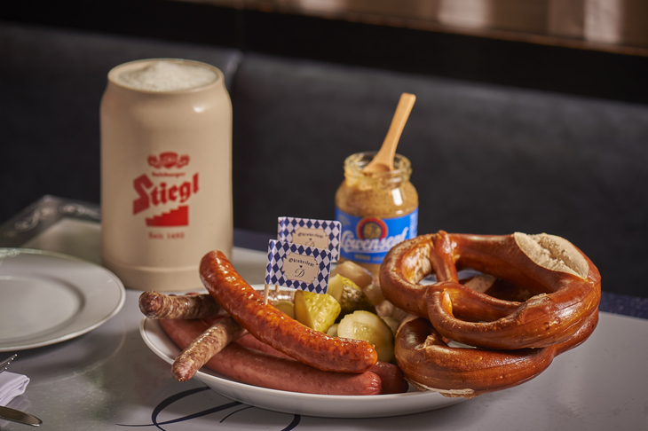 A spread of beer, pretzel and sausage