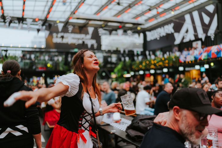A person in dirndl at Boxpark, with a beer