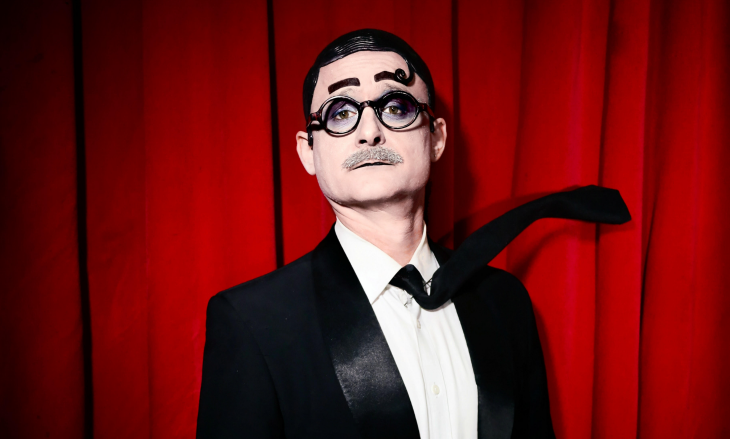 A striking looking cabaret performer with specs and a tache