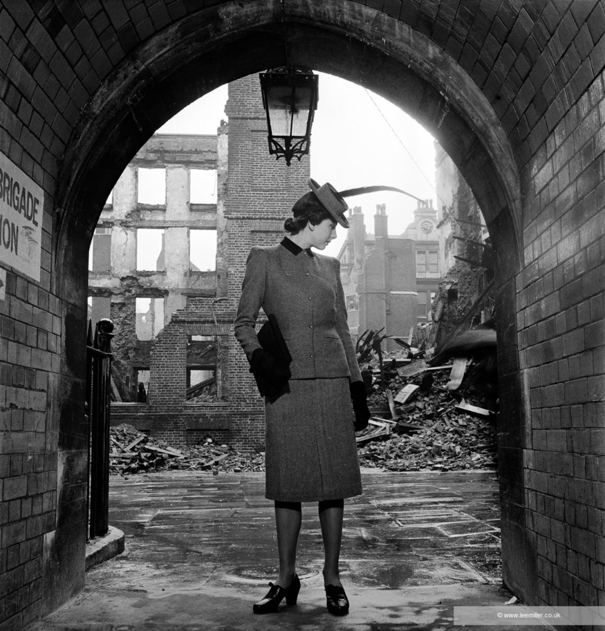 A woman standing in an archway in front of Blitz rubble