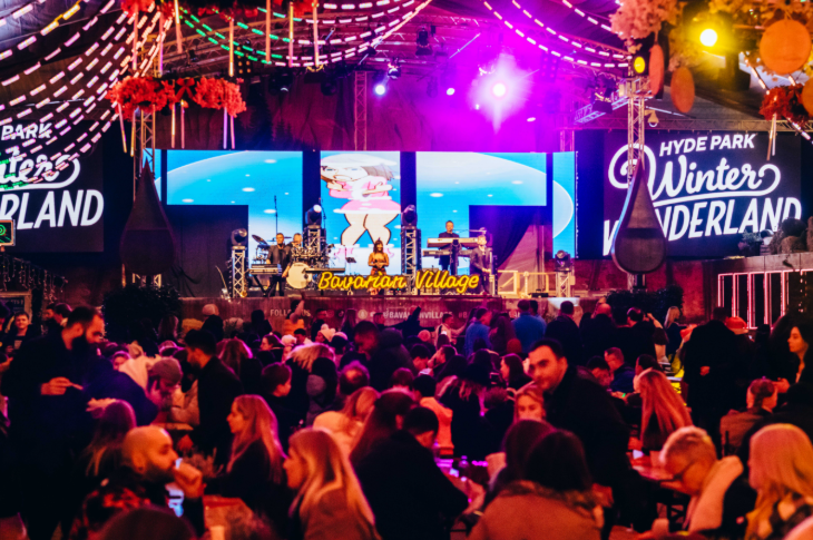 Hyde Park Winter Wonderland 2025: people sitting at benches inside a marquee eating and drinking