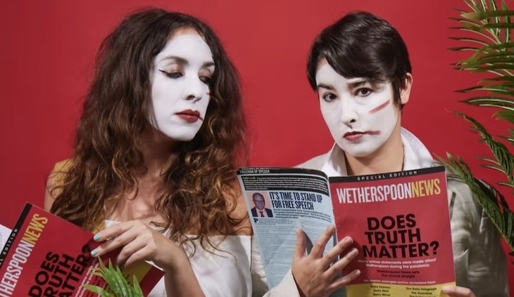 Two people in white facepaint reading Wetherspoon news