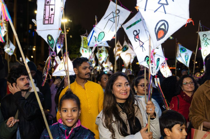 Diwali 2025 in London:  people holding up glowing lanterns in a parade