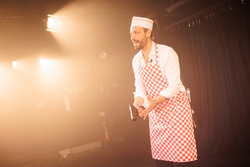 A man in a chef's outfit holding s handgun