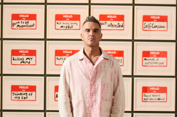 Things to do in London in October 2025: A photograph of Robbie Williams standing in front of his artworks