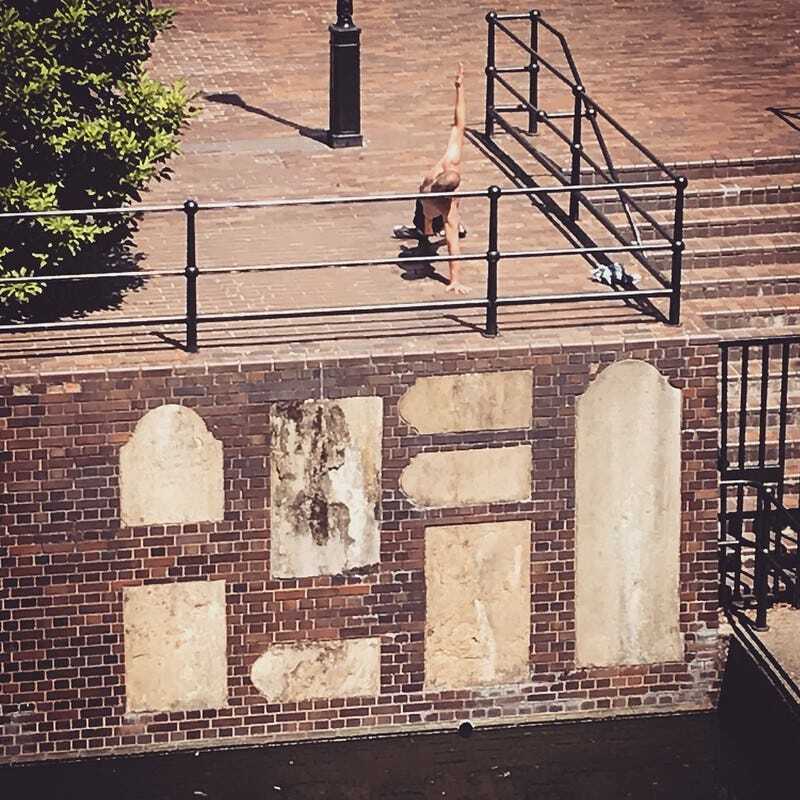 A man doing yoga in the barbican above some graves