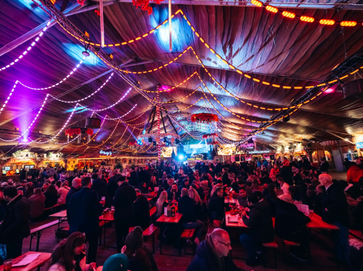 Hyde Park Winter Wonderland 2025: people sitting at benches eating and drinking inside a marquee at Hyde Park Winter Wonderland 2025
