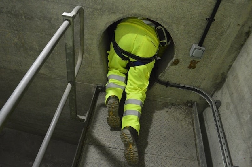 Legs in high vis, disappearing into a hole in some concrete