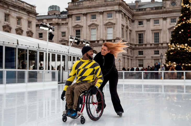 Christmas 2025 ice skating rinks in London: a woman pushing a man in a wheelchair around an ice skating rink at Somerset House 