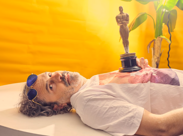Things to do in London today:  a man laying down, balancing an Oscars statue on his stomach