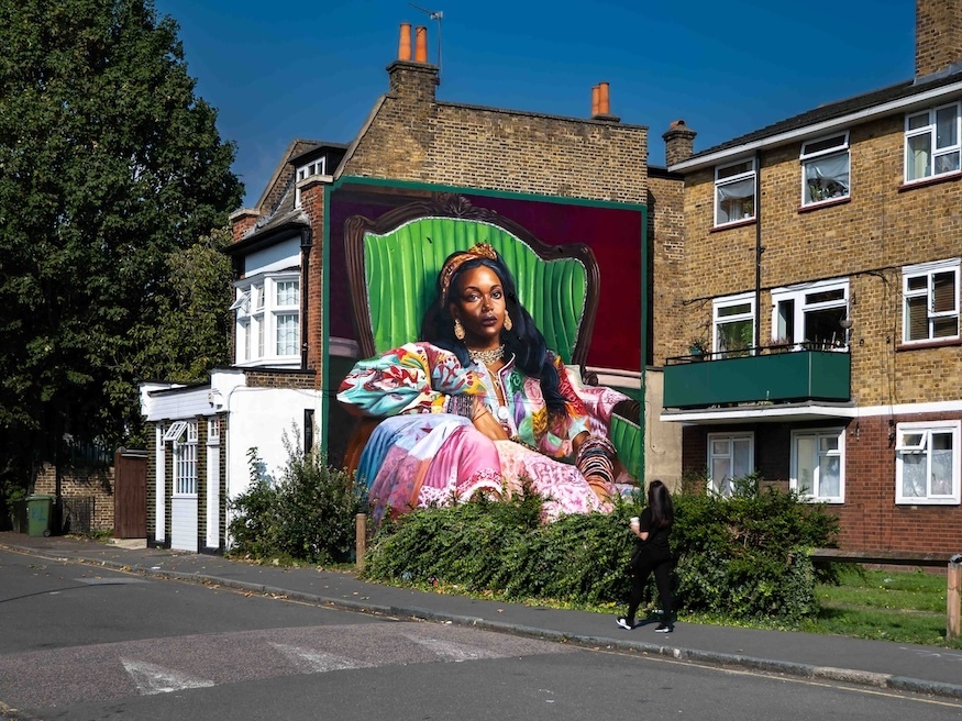 A mural in lee of a woman in a green chair by wedo goas