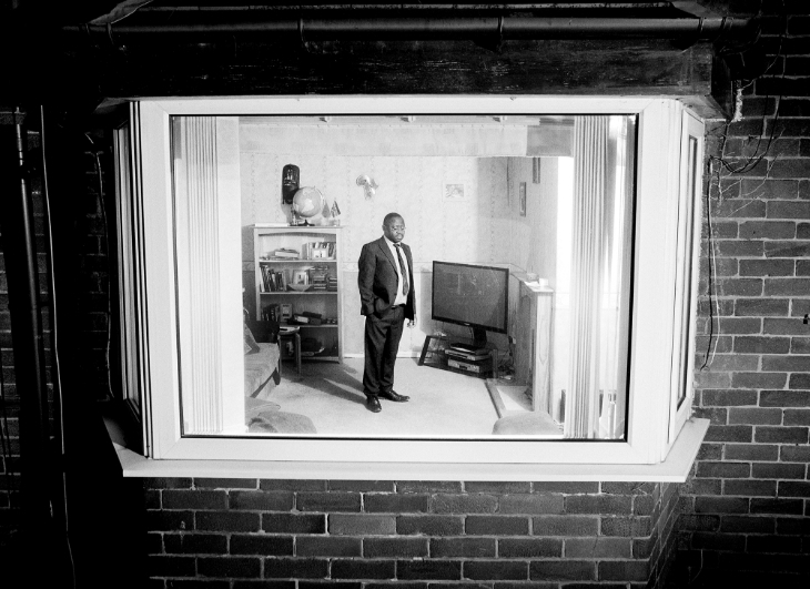 What's on today in London: a black and white photograph through a window of a man in a suit standing in a living room