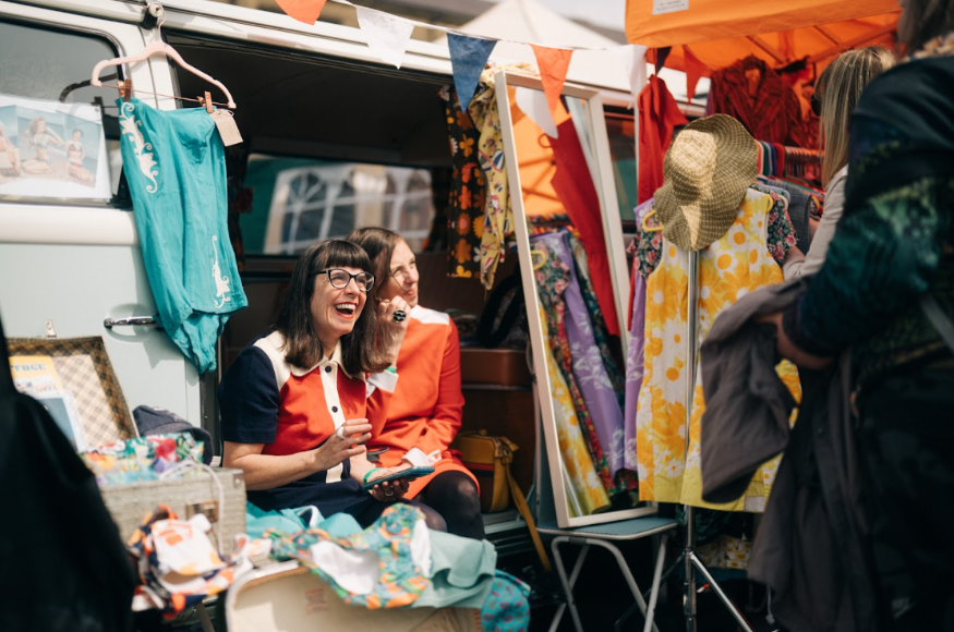 Things to do in London this weekend: two women sitting in a camper van, surrounded by rails of clothes