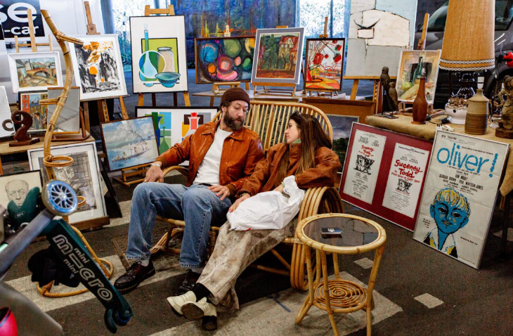 Things to do in London this weekend: two people sitting in a chair surrounded by homewares for sale at a flea market