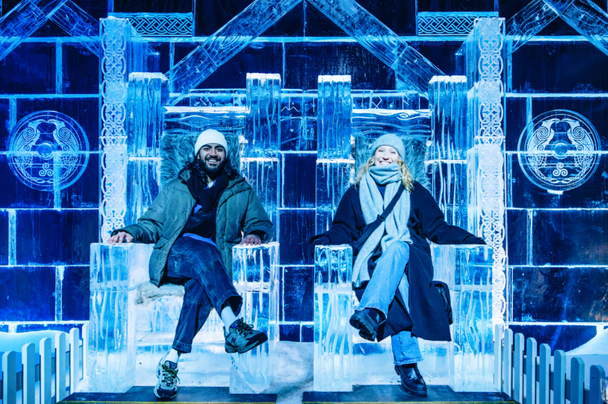 Hyde Park Winter Wonderland 2025: A man an woman dressed for winter sitting on a pair of ice thrones in the Magical Ice Kingdom at Hyde Park Winter Wonderland